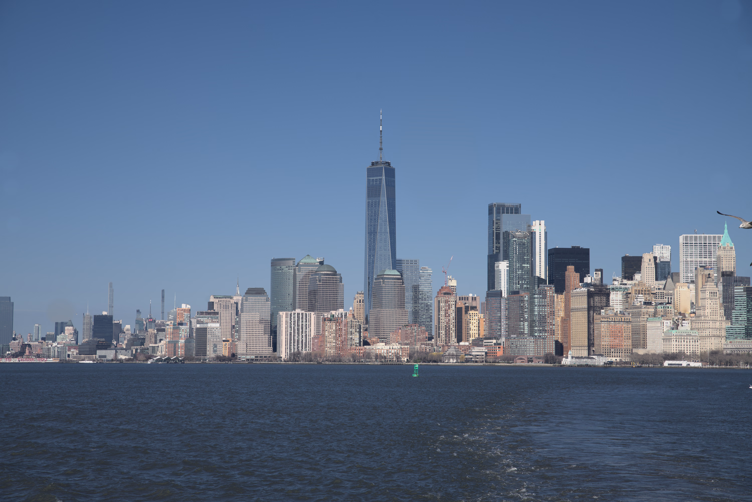 The lower Manhattan skyline stretches across dark blue water beneath a clear winter sky.