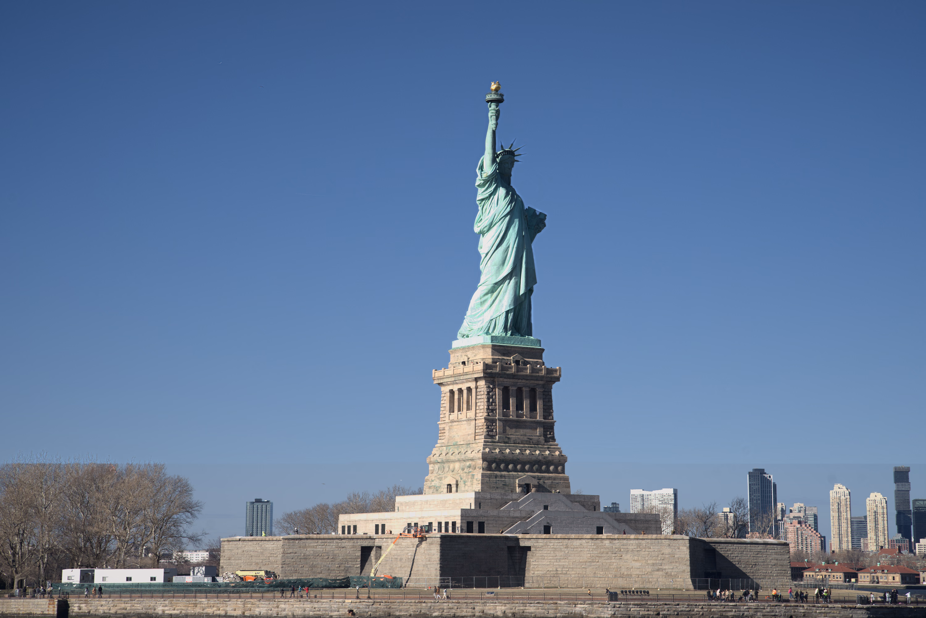 The Statue of Liberty and its stone pedestal rise against an uninterrupted field of deep blue sky.