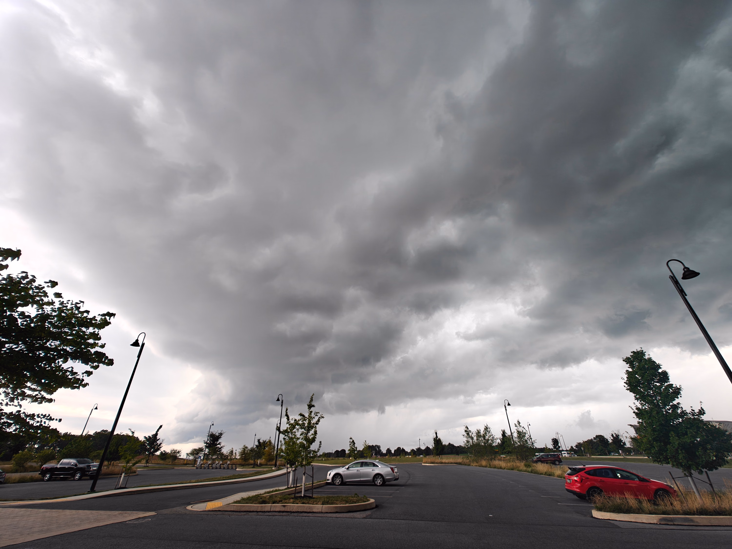 Dark storm clouds gather above a Hummelstown parking lot and line of cars.