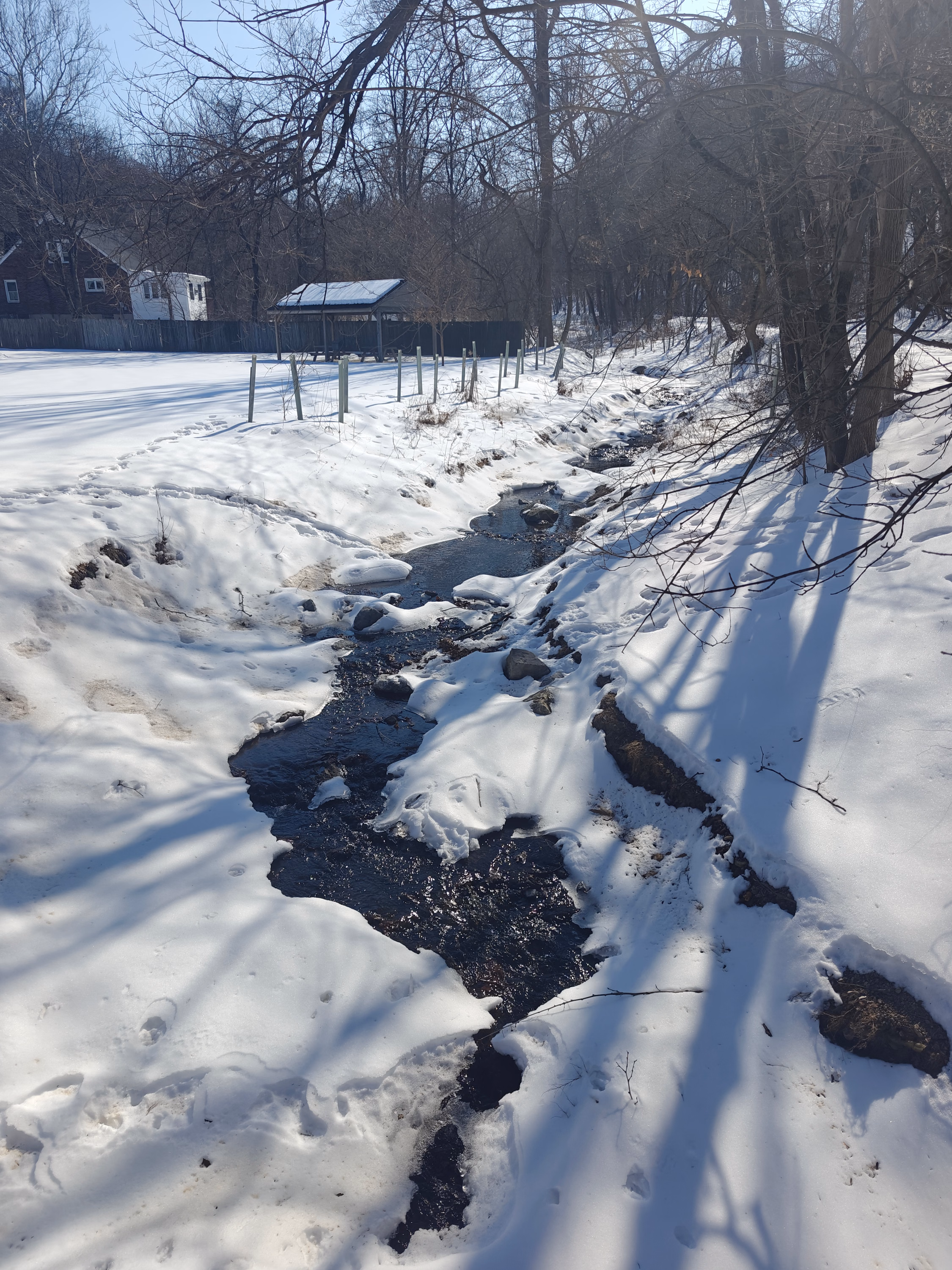 A narrow stream winds between snow-covered banks and winter trees near Hummelstown.