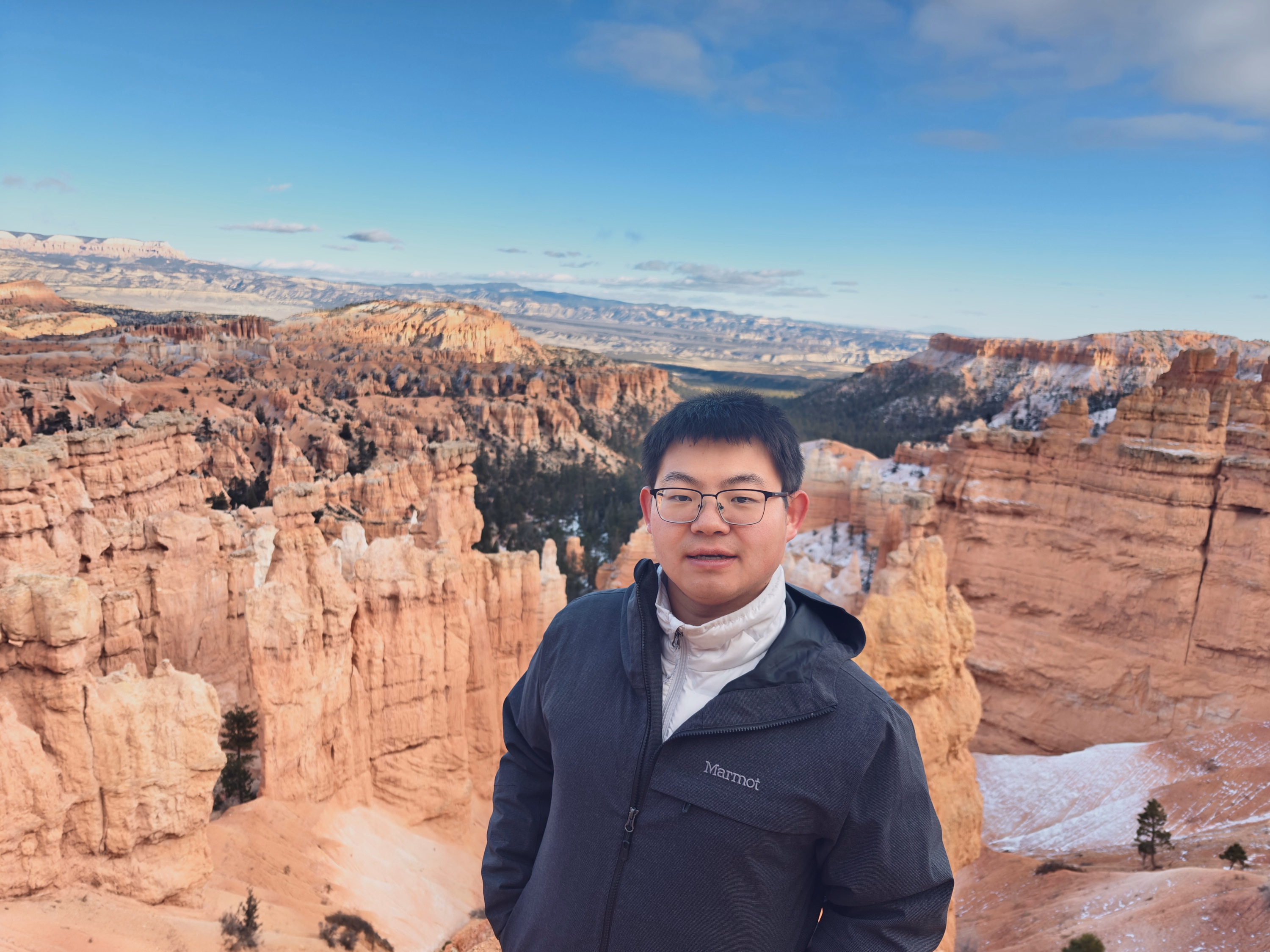 Jingyi stands at the Bryce Canyon rim with snow-dusted hoodoos filling the background.