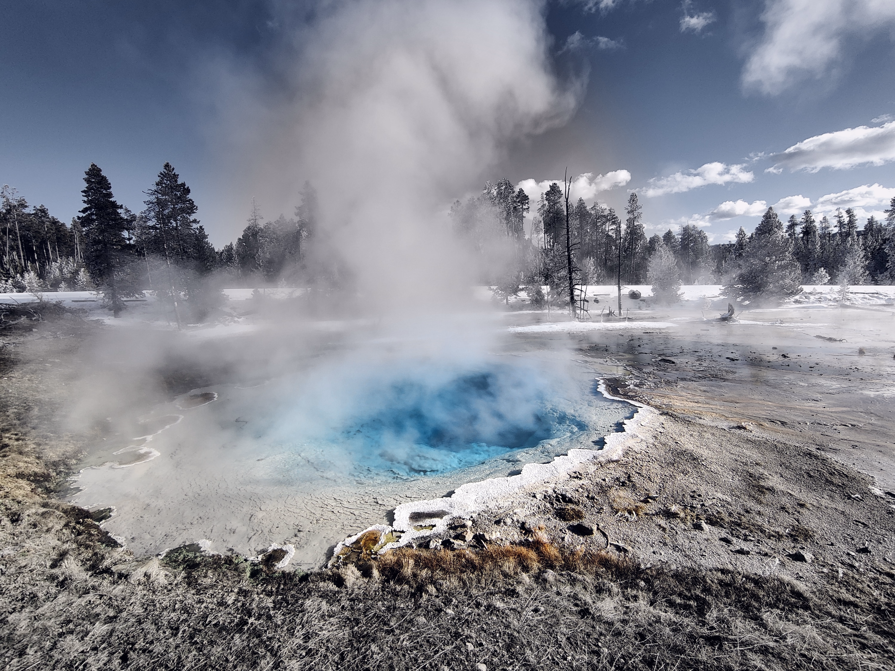 Turquoise water glows beneath rising steam in a close geothermal pool.