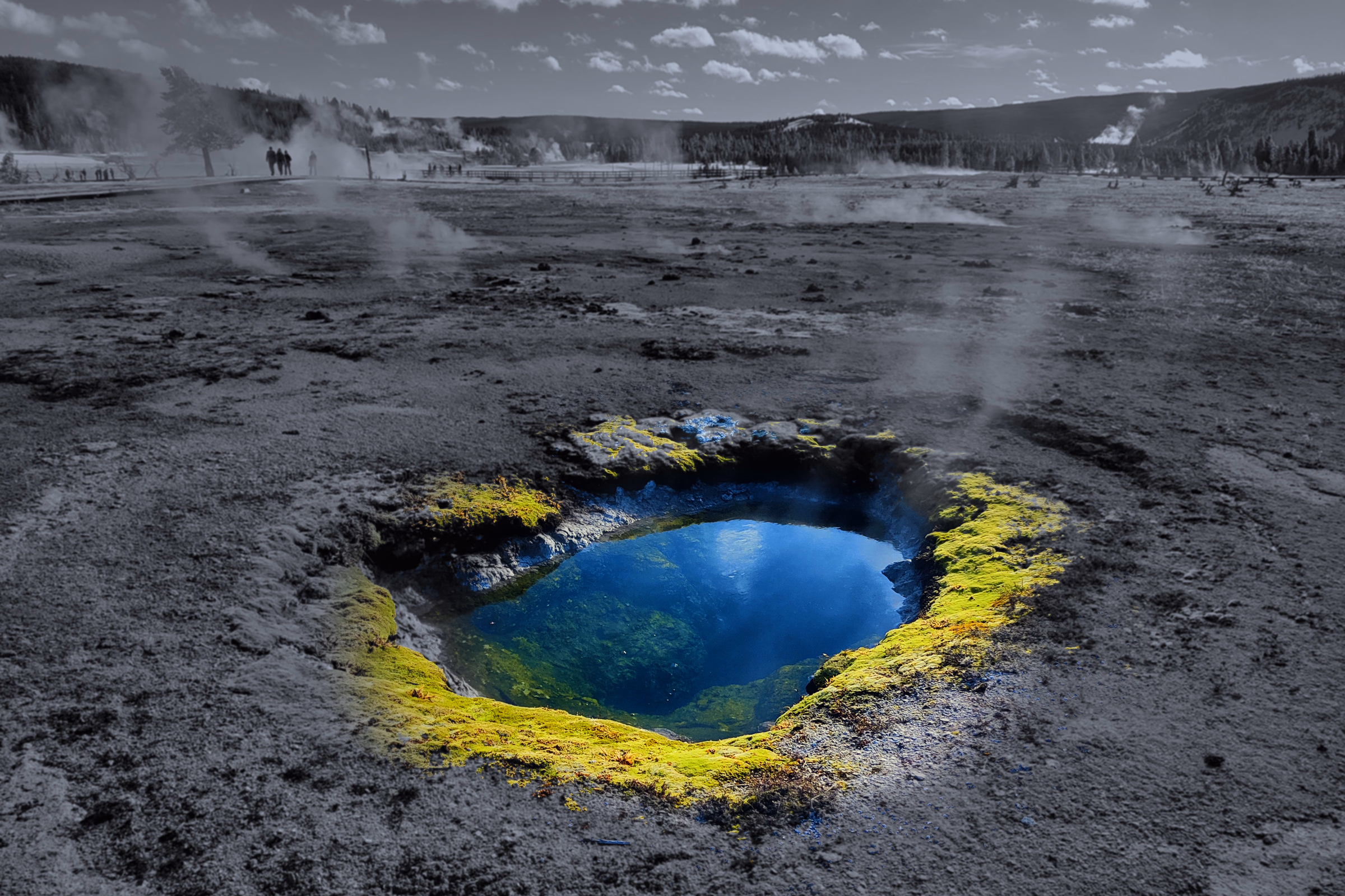 A mineral spring glows blue and yellow-green beneath a graphite winter basin and a broad monochrome sky.